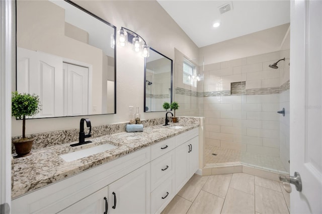 bathroom with tile patterned flooring, vanity, and a tile shower