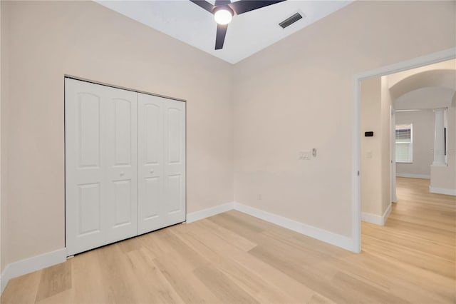 unfurnished bedroom with a closet, ornate columns, hardwood / wood-style flooring, and ceiling fan