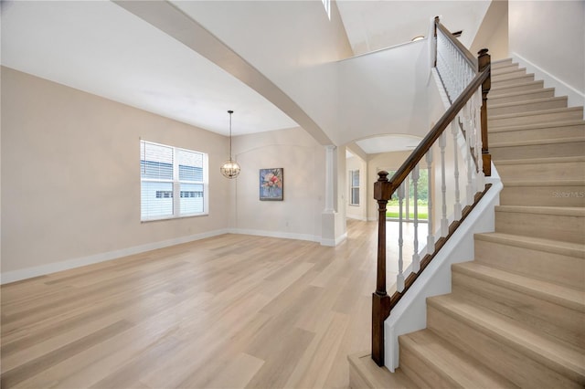 interior space with ornate columns, light hardwood / wood-style flooring, and an inviting chandelier