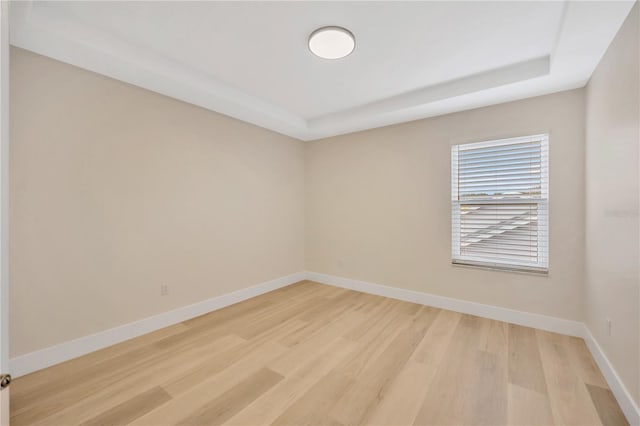 unfurnished room featuring a tray ceiling and light hardwood / wood-style flooring