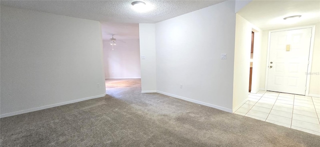 spare room with light colored carpet, a textured ceiling, and ceiling fan