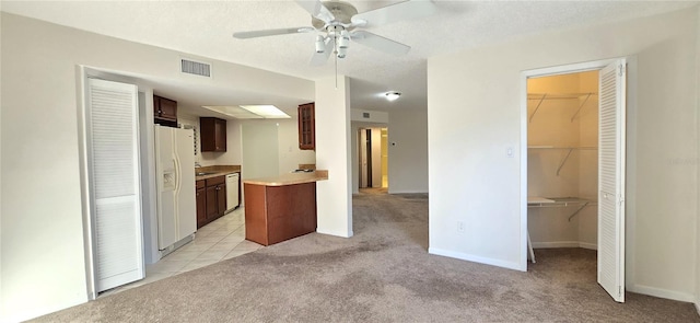 kitchen with light colored carpet, dark brown cabinetry, a textured ceiling, ceiling fan, and white appliances