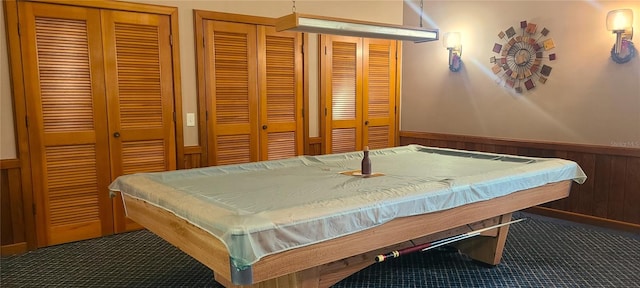 bedroom featuring pool table, multiple closets, and wooden walls