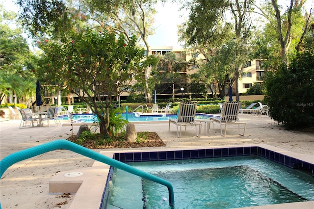 view of pool featuring a hot tub and a patio area