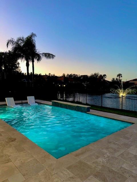 pool at dusk featuring a water view