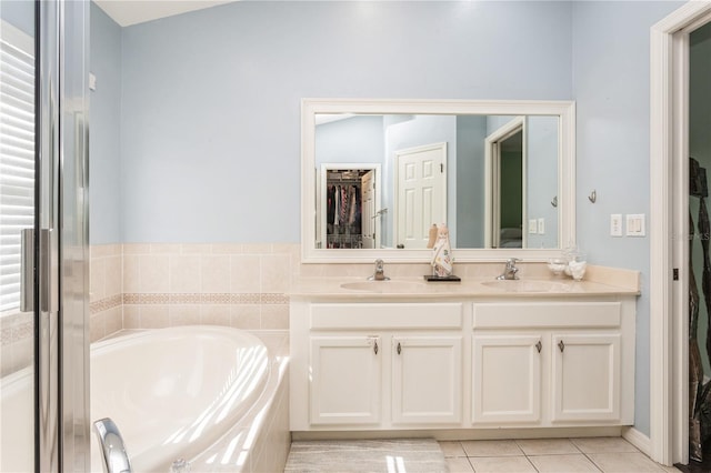 bathroom with tile patterned flooring, vanity, vaulted ceiling, and tiled tub