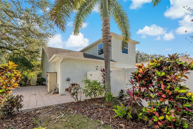 view of property exterior featuring stucco siding, fence, and a patio