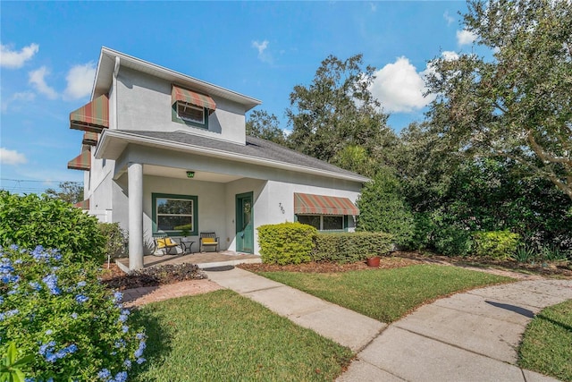 view of front of property featuring a front yard, a porch, and stucco siding