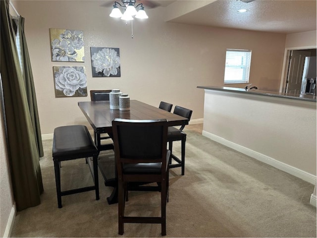 dining room with light carpet, baseboards, and a textured ceiling