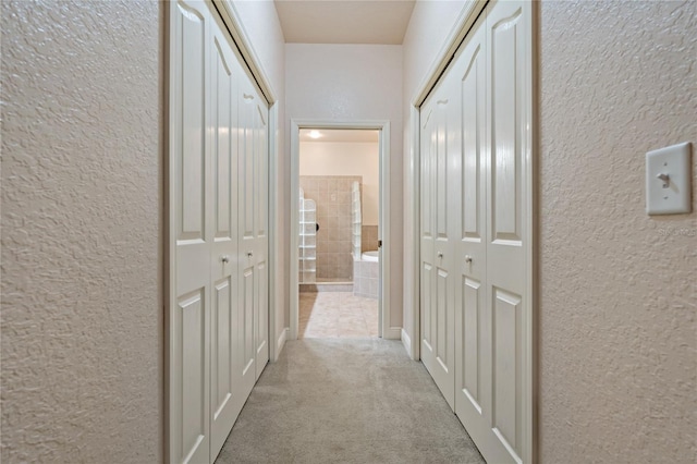 hallway featuring carpet flooring and a textured wall