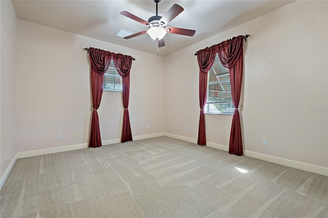 carpeted empty room featuring a ceiling fan, a wealth of natural light, and baseboards