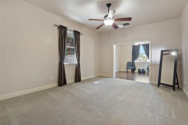 unfurnished room featuring carpet floors, visible vents, ceiling fan, and baseboards