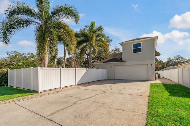 view of home's exterior featuring driveway, a lawn, an attached garage, fence, and stucco siding