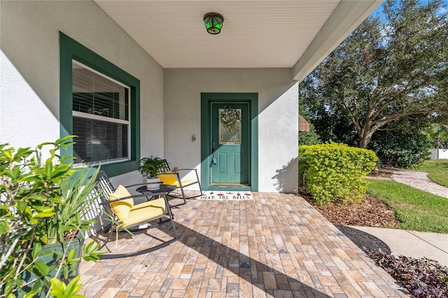 doorway to property featuring a porch and stucco siding