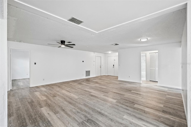 unfurnished living room with ceiling fan, a textured ceiling, and light hardwood / wood-style flooring