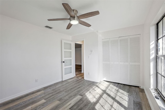 unfurnished bedroom with ceiling fan, a closet, and hardwood / wood-style flooring