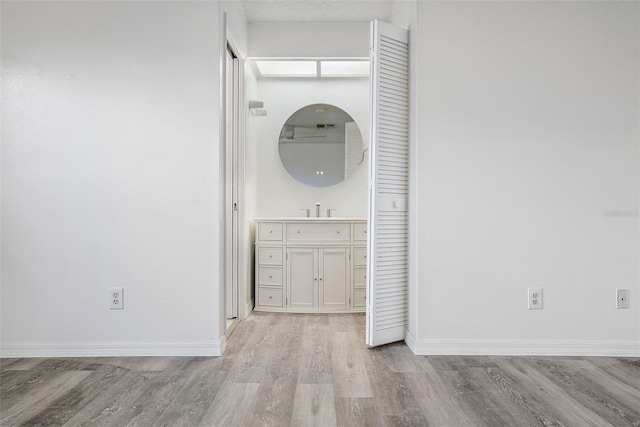 hallway with sink and light wood-type flooring