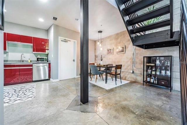 kitchen with visible vents, red cabinets, stainless steel appliances, concrete floors, and a sink