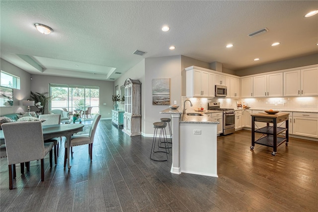 kitchen featuring sink, appliances with stainless steel finishes, a breakfast bar area, white cabinets, and dark hardwood / wood-style flooring