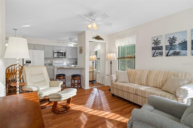 living room with light wood-type flooring, a textured ceiling, and ceiling fan