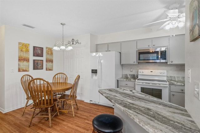 kitchen featuring ceiling fan with notable chandelier, decorative backsplash, gray cabinets, light wood-type flooring, and white appliances