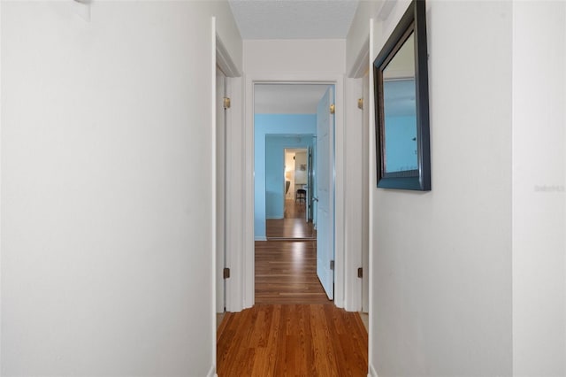 corridor featuring wood-type flooring and a textured ceiling