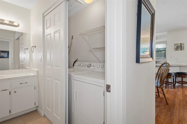 washroom with washing machine and clothes dryer and light hardwood / wood-style flooring