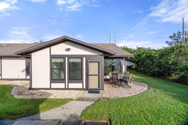 back of property with a lawn and a patio area