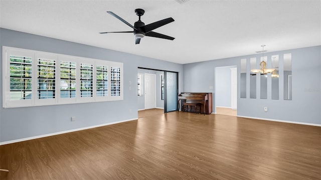 unfurnished living room featuring hardwood / wood-style flooring and ceiling fan with notable chandelier