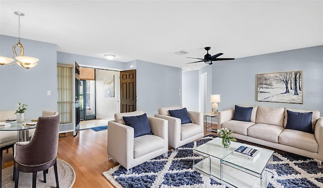 3499 Cedar Ln, Palm Harbor, FL 34684 - living area featuring light wood-style flooring, a ceiling fan, baseboards, and a chandelier