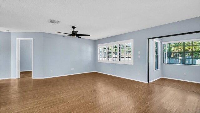3499 Cedar Ln, Palm Harbor, FL 34684 - spare room featuring plenty of natural light, wood finished floors, a ceiling fan, and baseboards