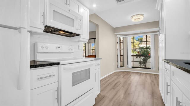 3499 Cedar Ln, Palm Harbor, FL 34684 - kitchen with white appliances, white cabinets, baseboards, and light wood-style floors