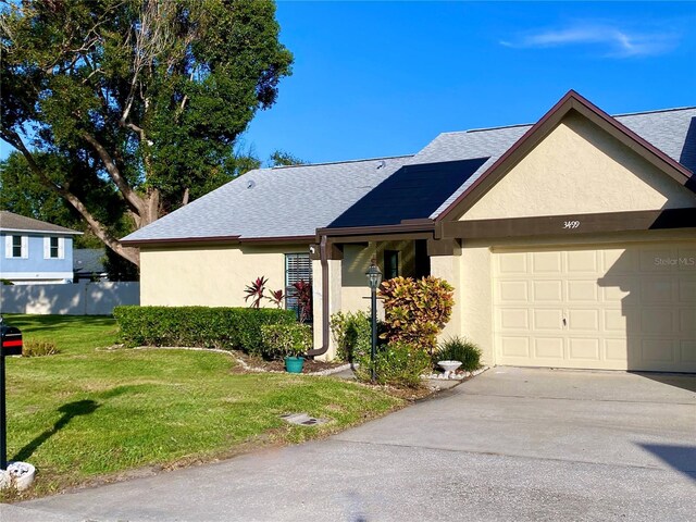 3499 Cedar Ln, Palm Harbor, FL 34684 - view of front of property with stucco siding, a front yard, concrete driveway, a garage, and roof with shingles