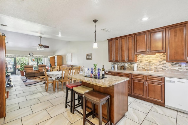 kitchen featuring dishwasher, sink, hanging light fixtures, ceiling fan, and a kitchen island