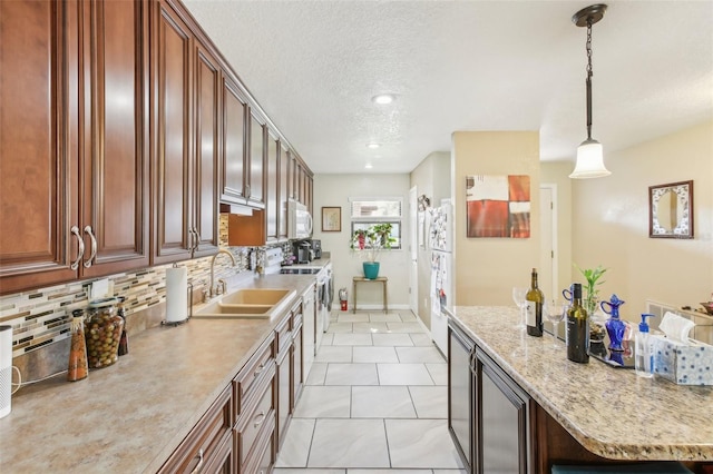 kitchen featuring a breakfast bar, backsplash, sink, hanging light fixtures, and light tile patterned floors