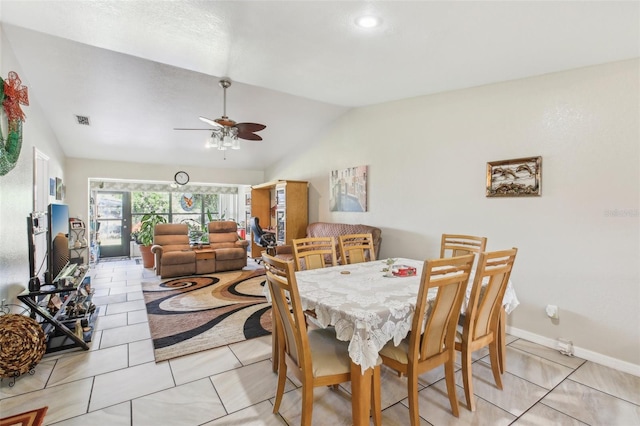 dining area with ceiling fan, light tile patterned floors, and vaulted ceiling