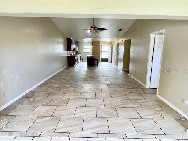 hall with lofted ceiling and light tile patterned floors