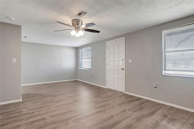 empty room featuring a textured ceiling, light hardwood / wood-style flooring, and ceiling fan