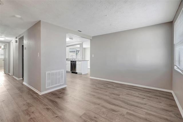 unfurnished room with plenty of natural light, a textured ceiling, and light hardwood / wood-style flooring