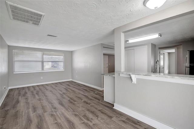 unfurnished living room featuring hardwood / wood-style flooring, a textured ceiling, and sink