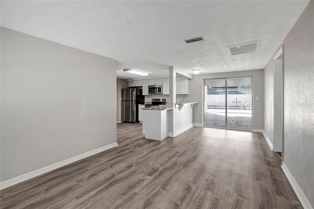 unfurnished living room with light hardwood / wood-style floors and a textured ceiling