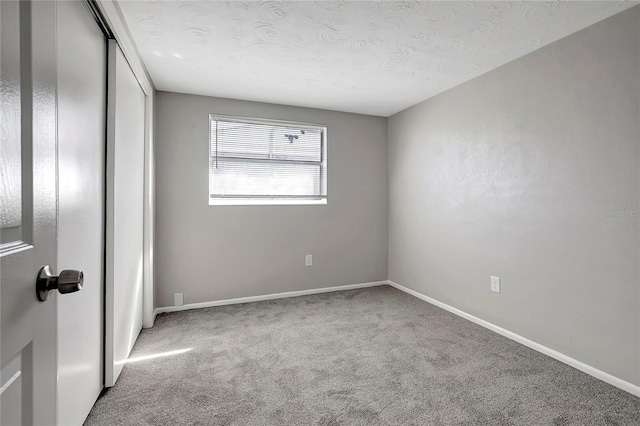 unfurnished bedroom featuring a textured ceiling, a closet, and carpet