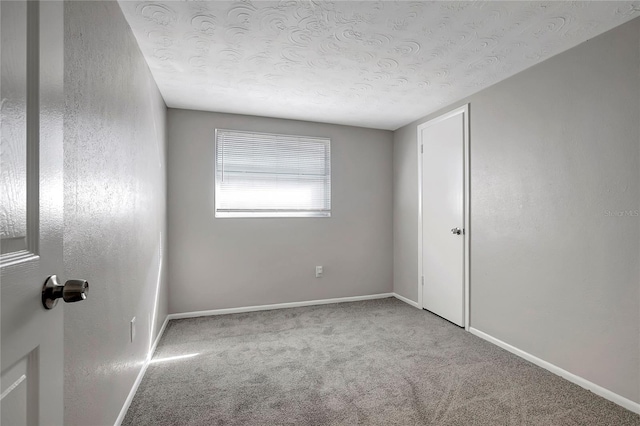 spare room featuring a textured ceiling and light colored carpet