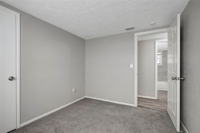 carpeted spare room with a textured ceiling