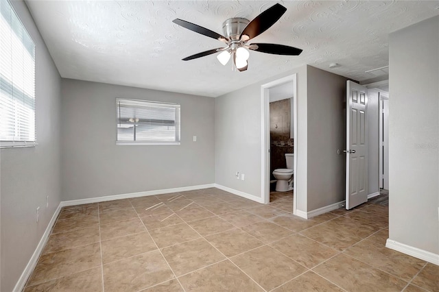 spare room featuring a textured ceiling, light tile patterned floors, ceiling fan, and plenty of natural light