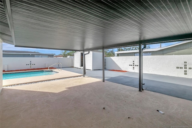 view of pool featuring a patio and a shed