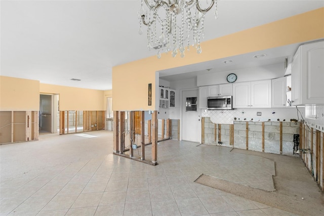 kitchen featuring white cabinets, light tile patterned flooring, a chandelier, and backsplash