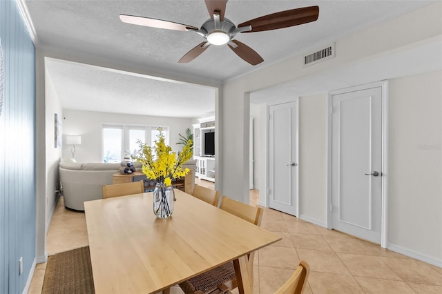 tiled dining space with ceiling fan and a textured ceiling