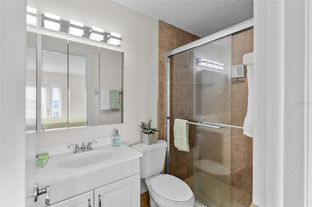 bathroom with vanity, a shower with shower door, a textured ceiling, and toilet