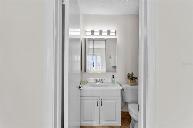 bathroom with tile patterned floors, toilet, vanity, and a textured ceiling